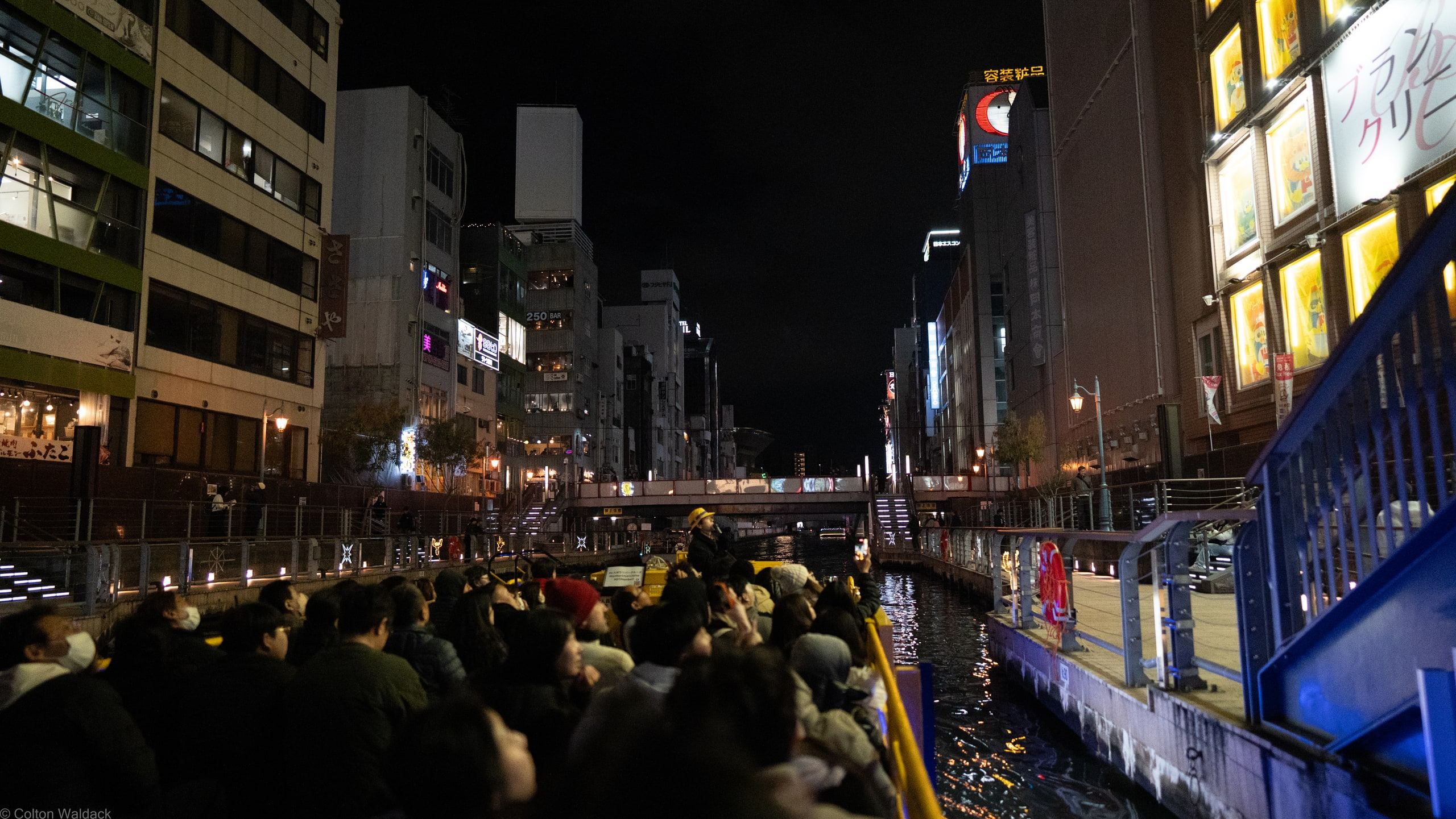 Crowd watching the Dotonbori canal at night with neon reflections