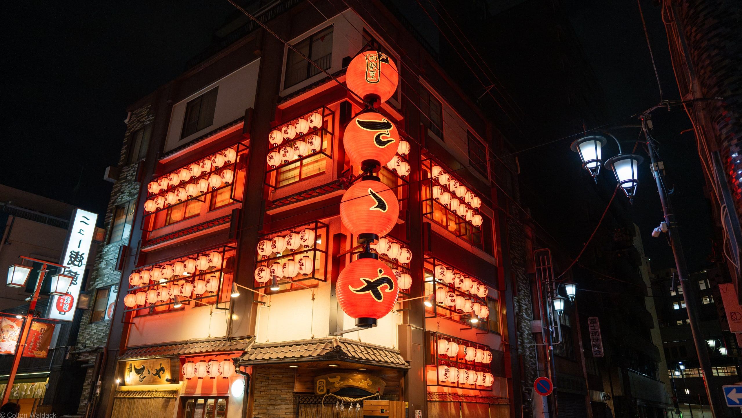 Corner izakaya covered wall to wall in glowing red lanterns at night