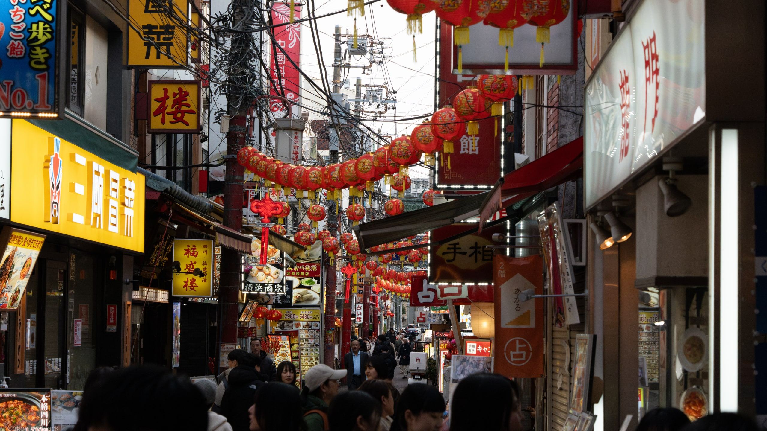 Crowded Yokohama Chinatown alley strung with red lanterns