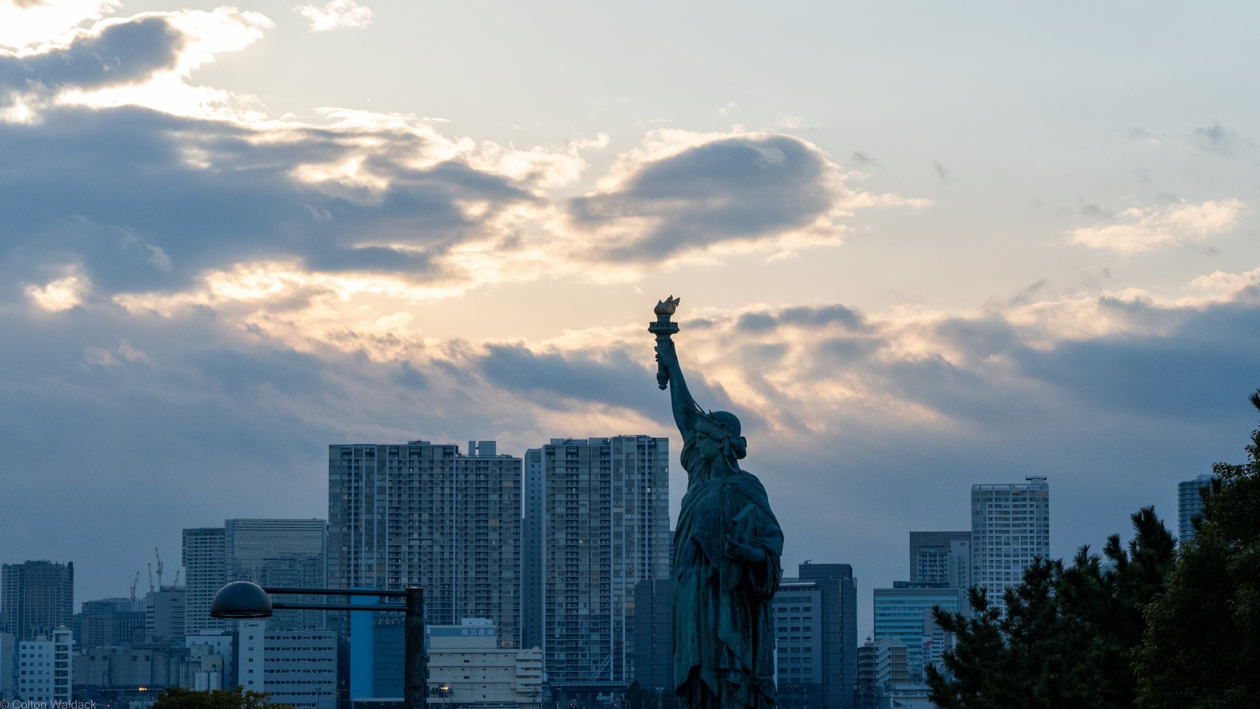Replica Statue of Liberty silhouetted against the Tokyo skyline at dusk