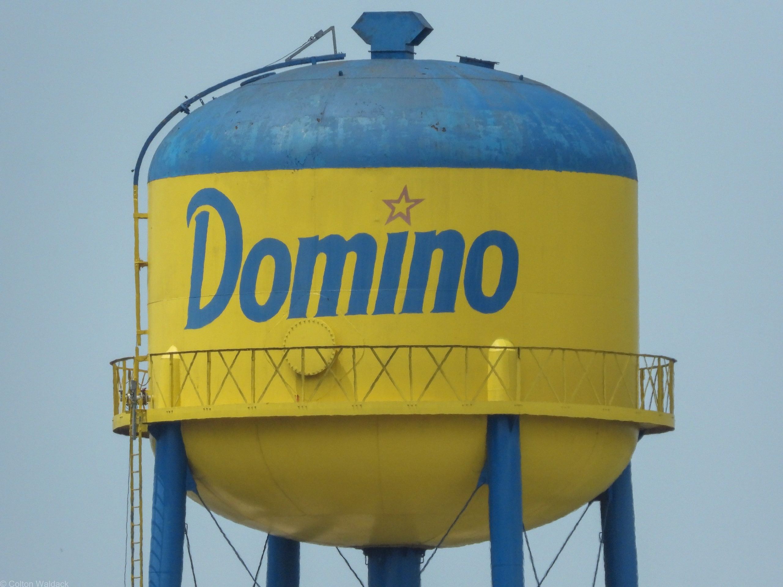 Yellow and blue Domino Sugar water tower against a clear sky
