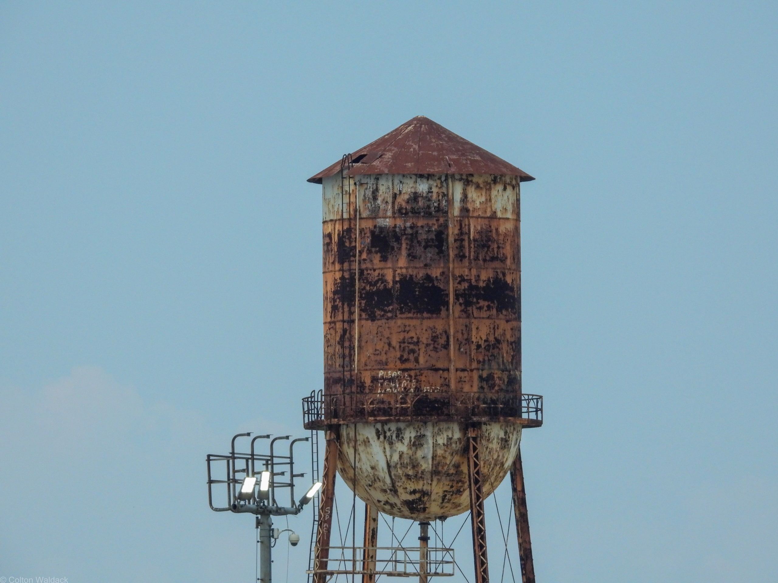 Rusted water tower standing against a pale sky